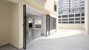 Un couloir intérieur au design moderne, doté d’une cloison vitrée et offrant une vue sur un immeuble à plusieurs étages.
