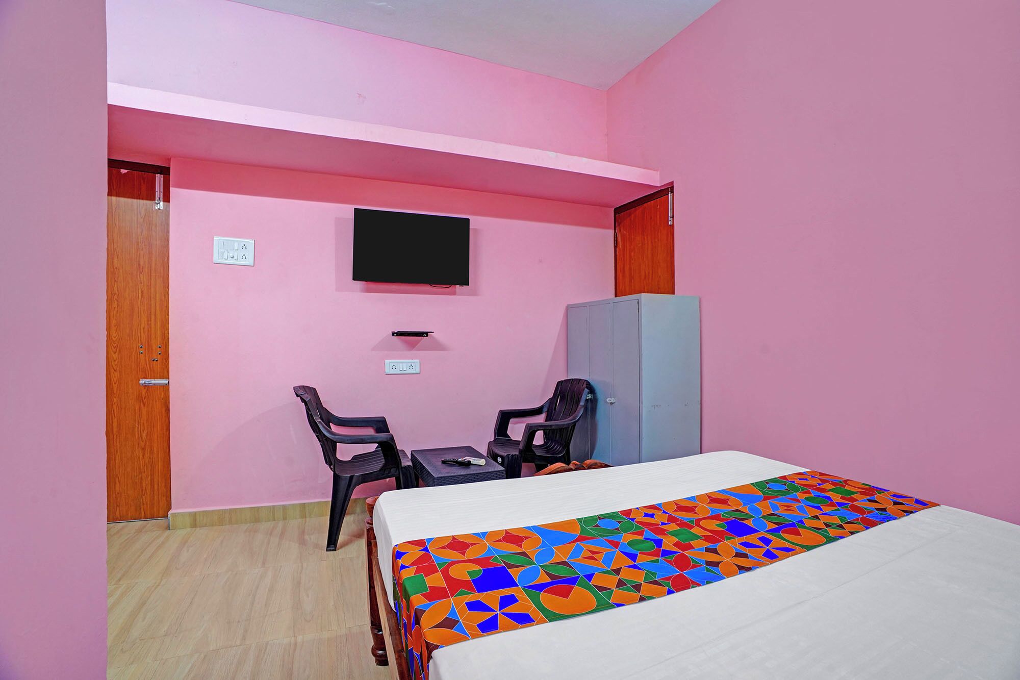 Una habitación con cama, escritorio, dos sillas, televisor y armario.