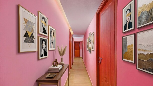 A hallway with pink walls, framed artwork, a wooden console table, and a red door. - Fabhotel Jay Jaga Residency (Chennai)
