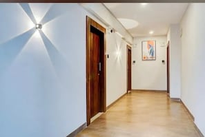 Un couloir avec une porte en bois, un luminaire et un tableau accroché au mur.