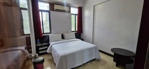 Une chambre d’hôtel équipée d’un lit, d’une petite table, d’une chaise, d’un téléviseur et d’un appareil de climatisation.