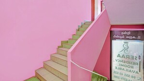 Una escalera rosa que conduce a una puerta con un letrero en tamil.