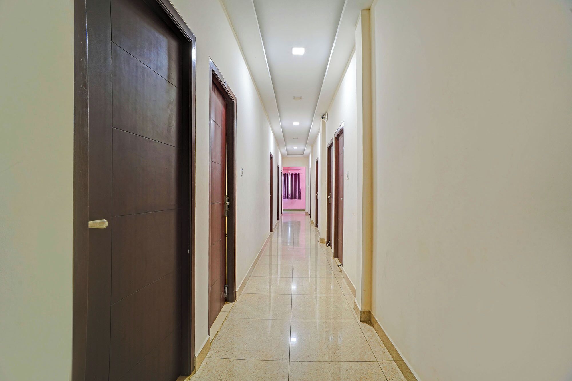 A long, narrow hallway with doors on both sides, leading to rooms.