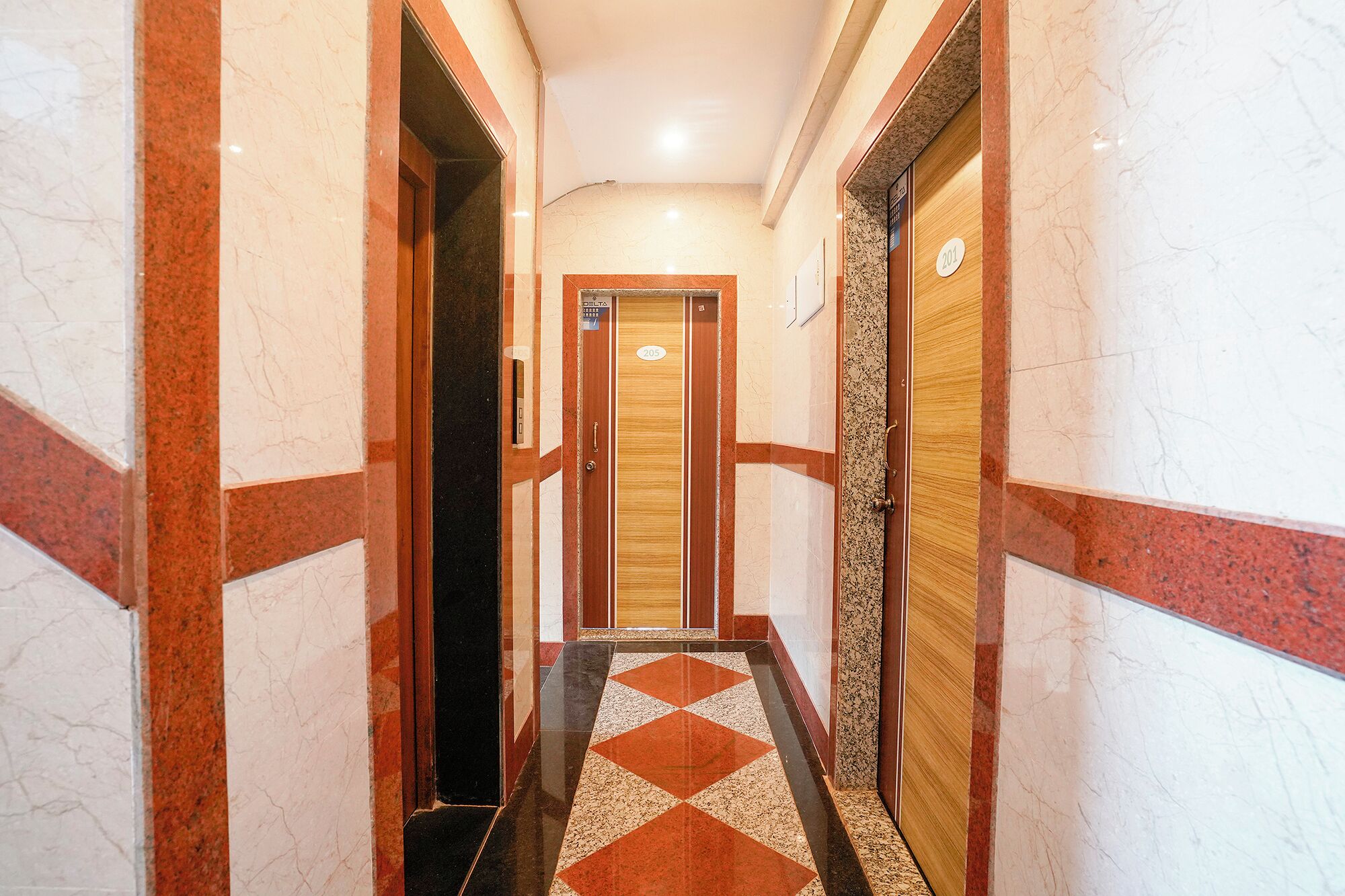 Un pasillo con paredes de mármol, suelo estampado y puertas con los números 201 y 205.
