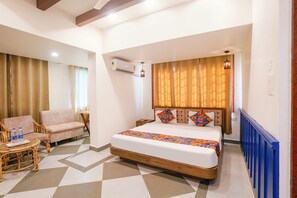 A hotel room with a bed, a chair, a small table, and a radiator.