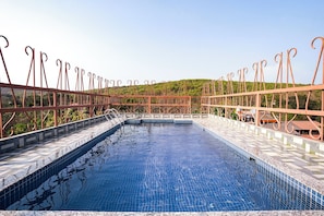 Una piscina en la azotea con barandilla metálica y solárium de baldosas.