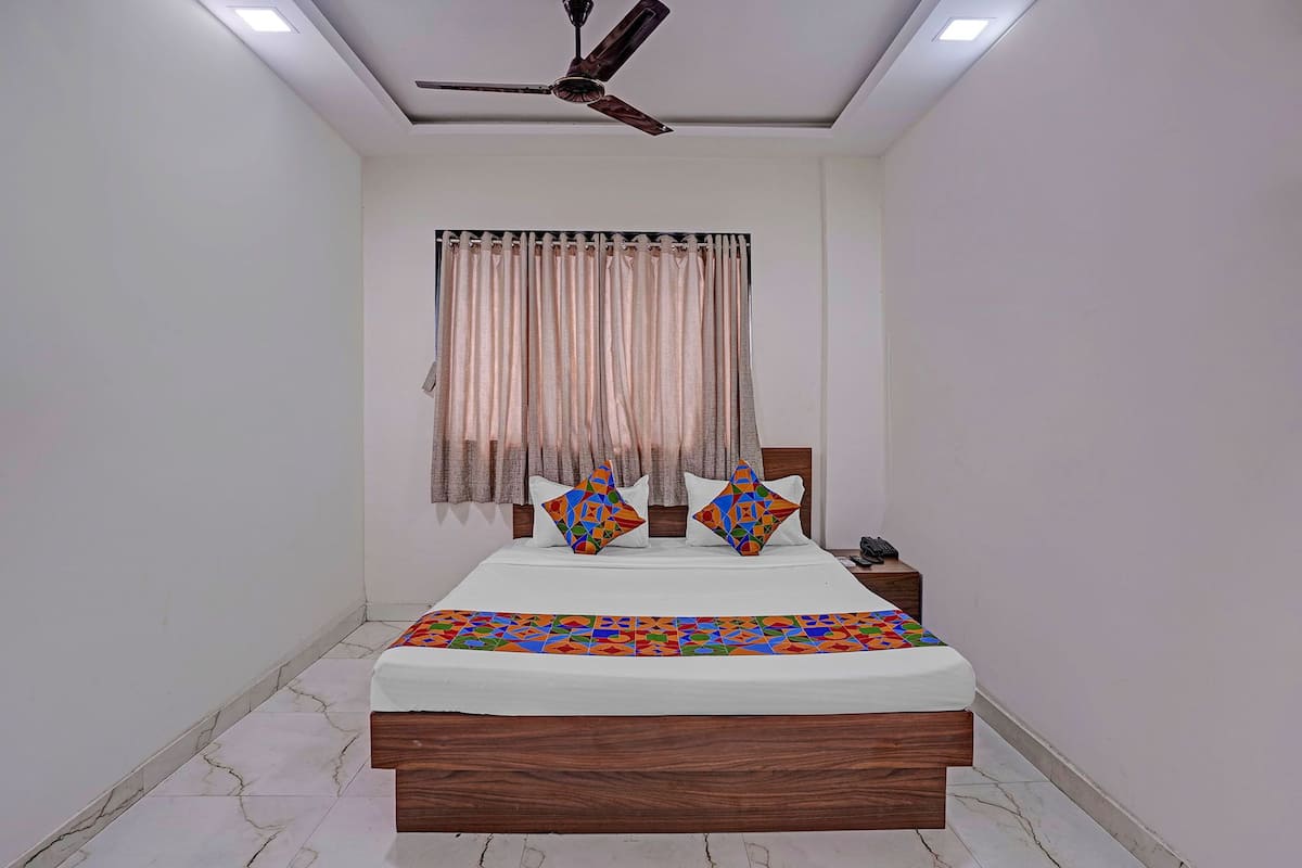 Un dormitorio con cama, cortinas, ventilador de techo y mesita de noche.
