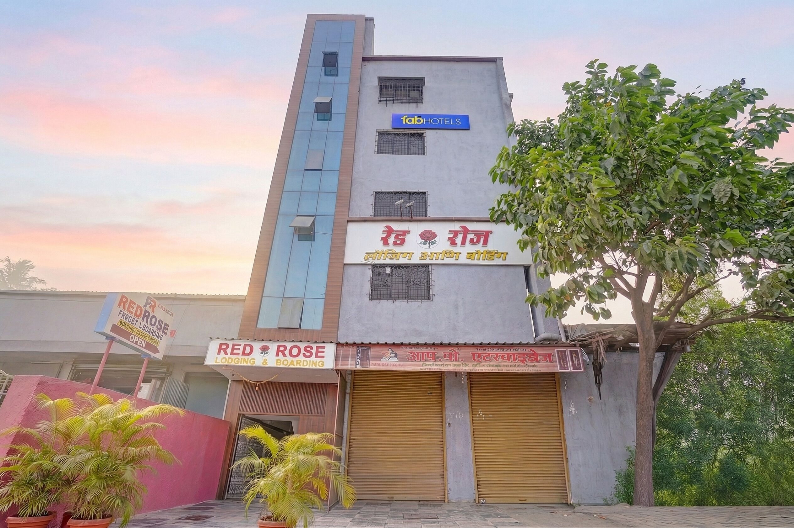 Un edificio con un letrero que dice 'fabHOTELS' y otro letrero que dice 'RED ROSE LODGING & BOARDING'.