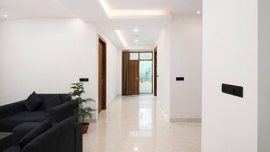 A modern hallway with a sofa set, a potted plant, and a wooden door leading to another room. - Fabhotel Park View (New Delhi)