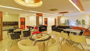 A modern hotel lobby with a seating area, a dining area, and a staircase. - Fabhotel Rudra Grand (Hyderabad)