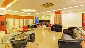 A hotel lobby with a dining area, a black leather sofa, and a reception desk. - Fabhotel Rudra Grand (Hyderabad)