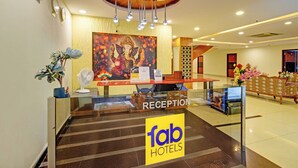 A reception area with a reception desk, a clock, a fan, and a painting of a deity. - Fabhotel Rudra Grand (Hyderabad)