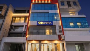 Un bâtiment d’hôtel moderne, avec une enseigne indiquant « fabHOTELS » et une plaque portant le nom « HOTEL THE ARROW ».