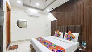 Une chambre d’hôtel avec un lit, une table de chevet avec une bouteille d’eau, un miroir et un ventilateur de plafond.