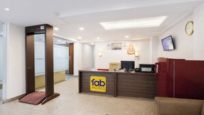 Zona de recepció d'hotel amb una taula, un rellotge i una televisió penjada a la paret.