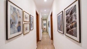Passadís amb quadres als murs, terra polita i portes de fusta.