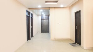 A hallway with closed doors, a tiled floor, and recessed lighting. - Fabhotel Mb Residency (New Delhi)