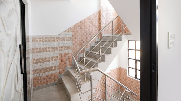 A staircase with metal railings, a tiled wall, and a window. - Fabhotel Mb Residency (New Delhi)