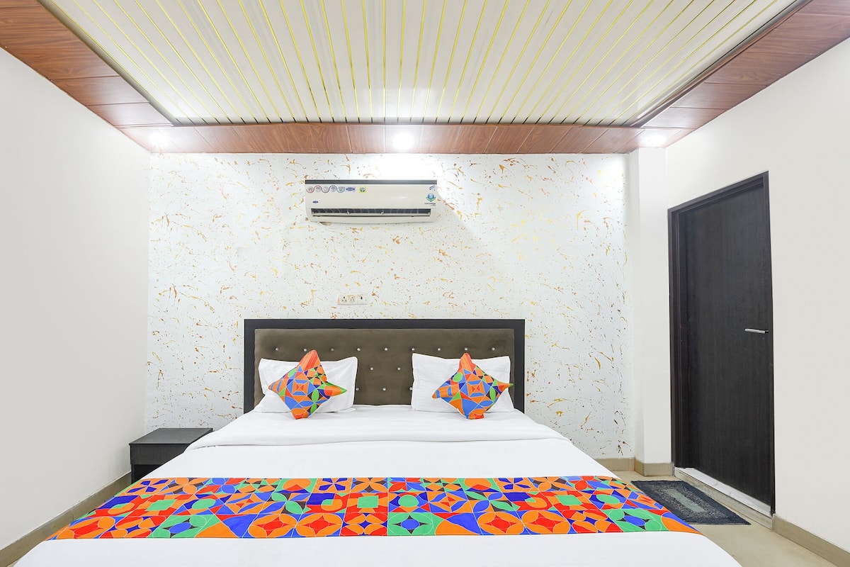 A bedroom with a bed, an air conditioning unit, a door, and a patterned carpet.