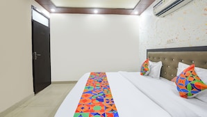 A hotel room with a bed, a headboard, a door, and an air conditioning unit. - Fabhotel Mb Residency (New Delhi)
