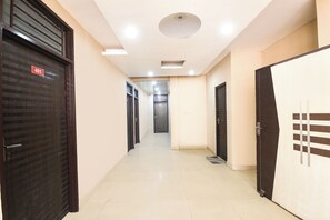 A corridor with closed doors, a ceiling light, and a tiled floor. - Fabhotel Mb Residency (New Delhi)