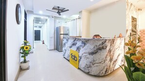 A hotel reception area with a marble counter, ceiling fans, and a sign for 'fab hotels'. - Fabhotel Mb Residency (New Delhi)