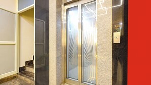 A modern elevator with glass doors and a metallic interior, adjacent to a marble staircase. - Fabhotel Lorven Grand (Visakhapatnam)