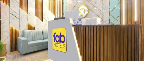 Een hotel receptie in modern design, met een receptiebalie, een blauwe bank en een marmeren wand met geometrische patronen.
