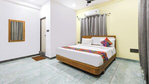 A bedroom with a bed, a ceiling fan, an air conditioning unit, and a window with curtains. - Fabhotel Lorven Grand (Visakhapatnam)