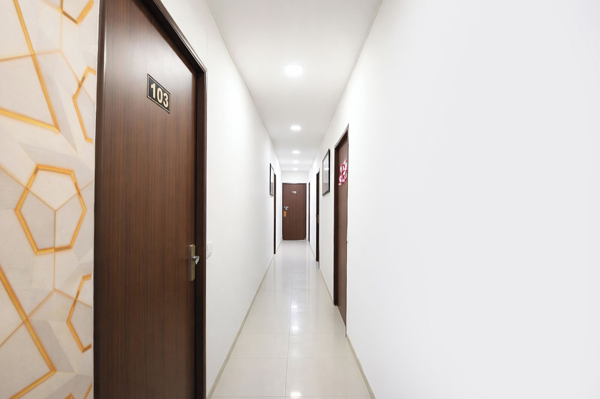 A hotel hallway with wooden doors, numbered 103 and 104, and a tiled floor.