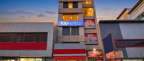 Un hotel de varios pisos con un llamativo letrero de 'fabHOTELS', numerosas ventanas y varios anuncios de 'HOTEL SNOW VALLEY'.