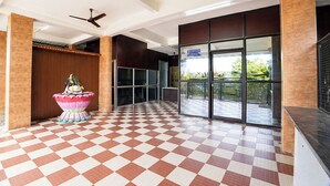A reception area with a checkered floor, a reception desk, a ceiling fan, and a view of the outside. - Fabhotel Madras Residency (Chennai)