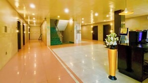Eine Hotelhalle mit einer Rezeption, einer Treppe und einem Blumenstrauß.