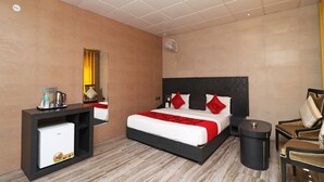 Ein Hotelzimmer mit Bett, Nachttisch, Spiegel und kleinem runden Tisch.
