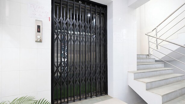 Un escalier avec une rampe en métal, une grille décorative noire et une enseigne sur le mur.