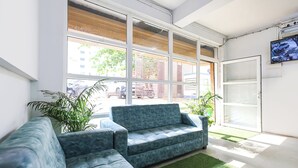 Un intérieur moderne avec un canapé d’angle, de grandes fenêtres et un téléviseur à écran plat.