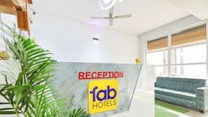 Un espace d’accueil avec un comptoir en marbre, un ventilateur de plafond et un canapé vert.