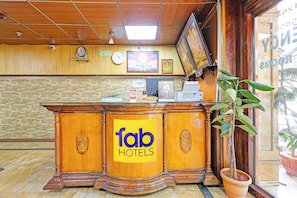 Un comptoir d’accueil avec une enseigne indiquant « fab hotels », une horloge et un tableau encadré au mur.