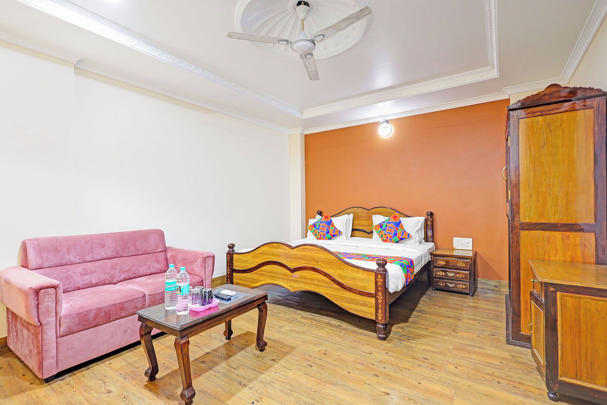 A bedroom with a bed, a pink sofa, a wooden coffee table, and a wardrobe.