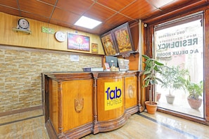 Una recepción con un cartel de 'Tab Hotels', un reloj, un cuadro enmarcado y una ventana con vista a un edificio.