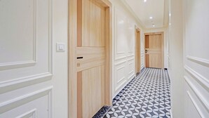 A hallway with wooden doors, white walls, and a patterned floor. - Fabhotel Symphony Regency (Varanasi)