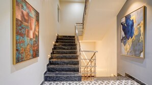A staircase with marble steps and a metal railing, flanked by two large abstract paintings. - Fabhotel Symphony Regency (Varanasi)
