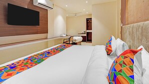 A hotel room with a bed, a flat-screen TV mounted on the wall, a desk with a chair, and a wardrobe. - Fabhotel Symphony Regency (Varanasi)