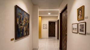 A hallway with framed artwork on the walls, a wooden door with a number, and a tiled floor.
