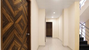 A hallway with a wooden door, a staircase, and a door in the distance.