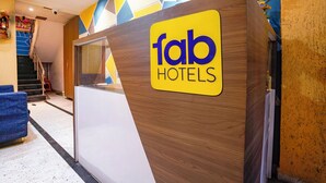 A reception desk with a 'fab hotels' sign, a blue chair, and a staircase in the background.