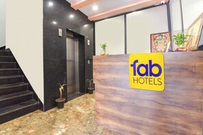 A hotel reception desk with a marble floor, a staircase, and a security camera.