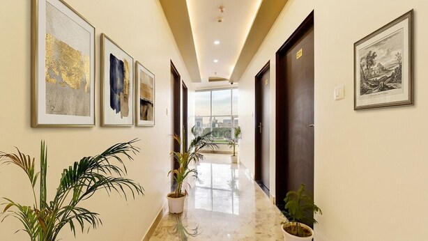 A hallway with framed artwork, potted plants, and a view to the outside. - Fabhotel Dream Stay (Jaipur)