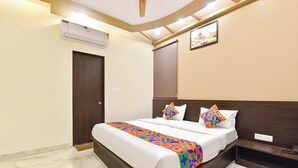 A hotel room with a bed, a bedside table, an air conditioning unit, a door, and a wall-mounted picture. - Fabhotel Dream Stay (Jaipur)