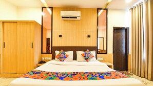 A hotel room with a large bed, a wardrobe, an air conditioning unit, and a door with curtains. - Fabhotel Madhuban (Jaipur)